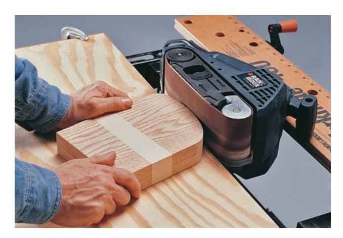Clamp a belt sander and a scrap board to the workbench to create a stationary shaping tool.