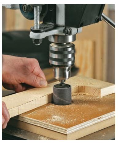 Using a drum sander attachment in a drill press to smooth curved edges.