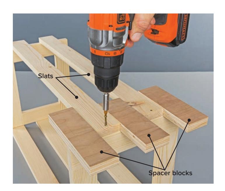 Attaching slats to end frames using spacers and screws.