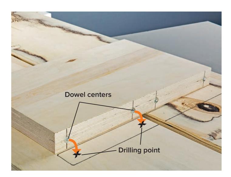 Dowel centers inserted into the drilled holes on the top of a leg, ready to mark the tabletop.