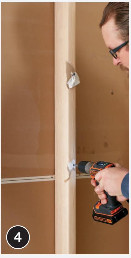 Worker prying loose wall covering with a wrecking bar.