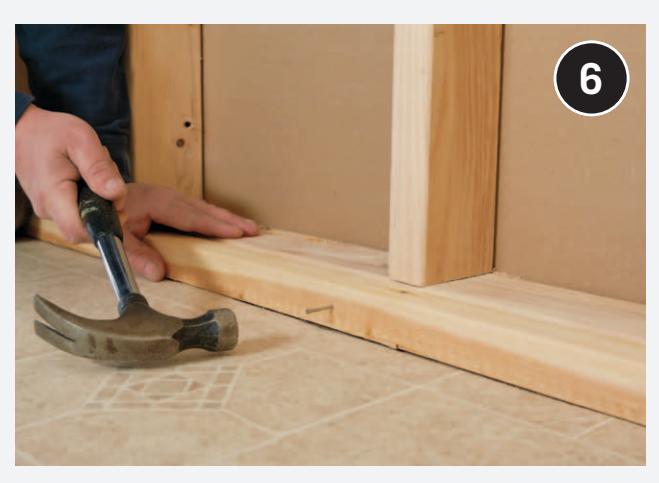 Applying construction adhesive to a furring strip.