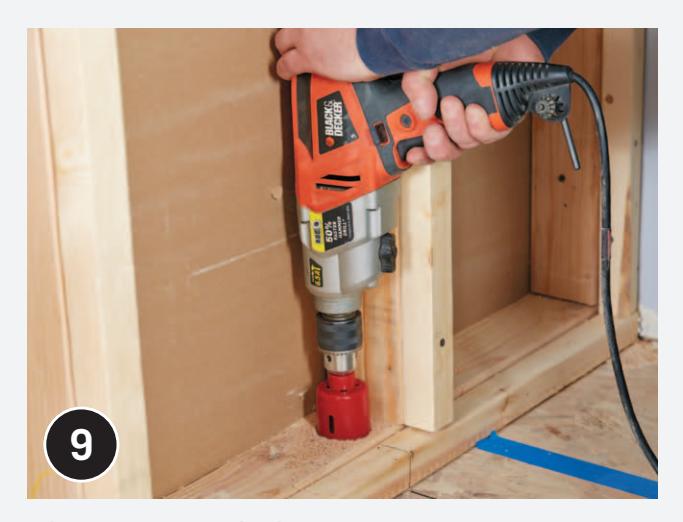 Drilling a large hole for a drain pipe with a hole saw.
