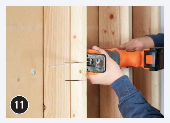 Cutting notches in wall studs for plumbing lines.
