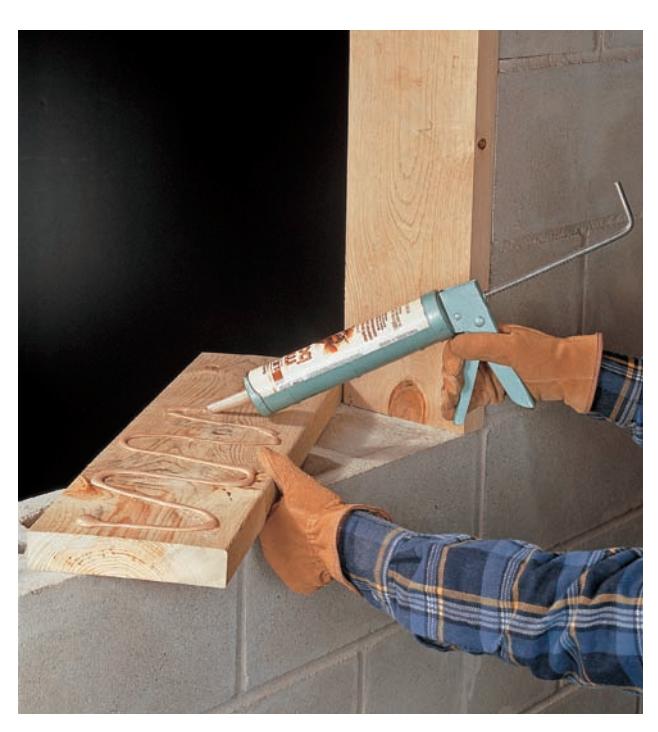 Applying exterior-grade construction adhesive to a foundation