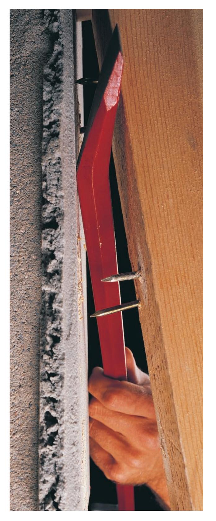 A flat bar being used to pry a piece of wood.