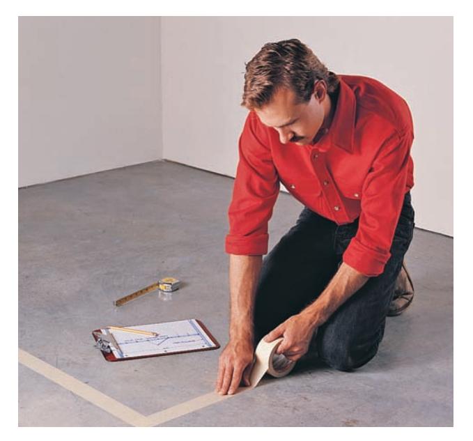 Using masking tape to lay out a carpentry project on the floor