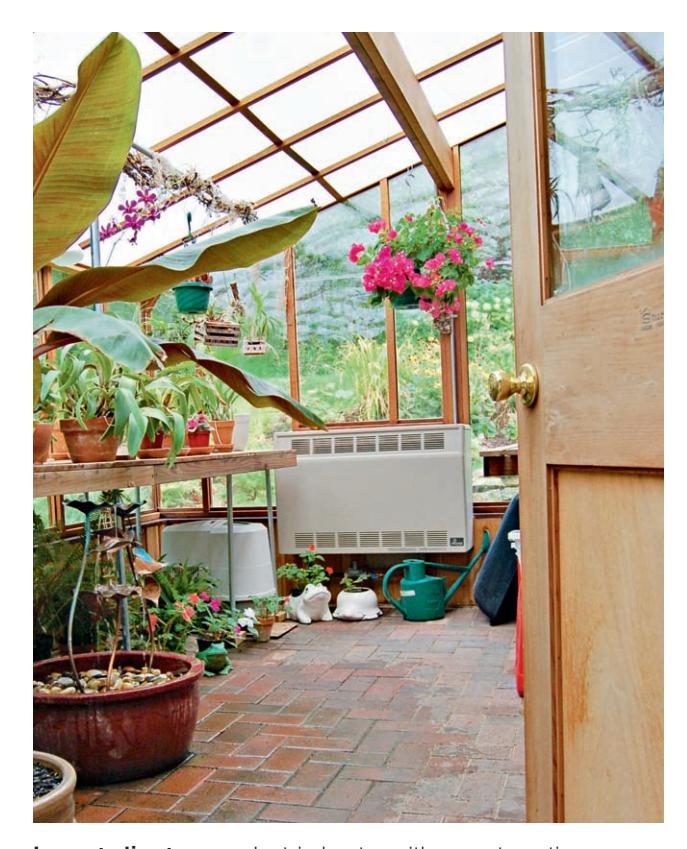 An electric heater with a fan in a greenhouse, positioned to distribute warm air.