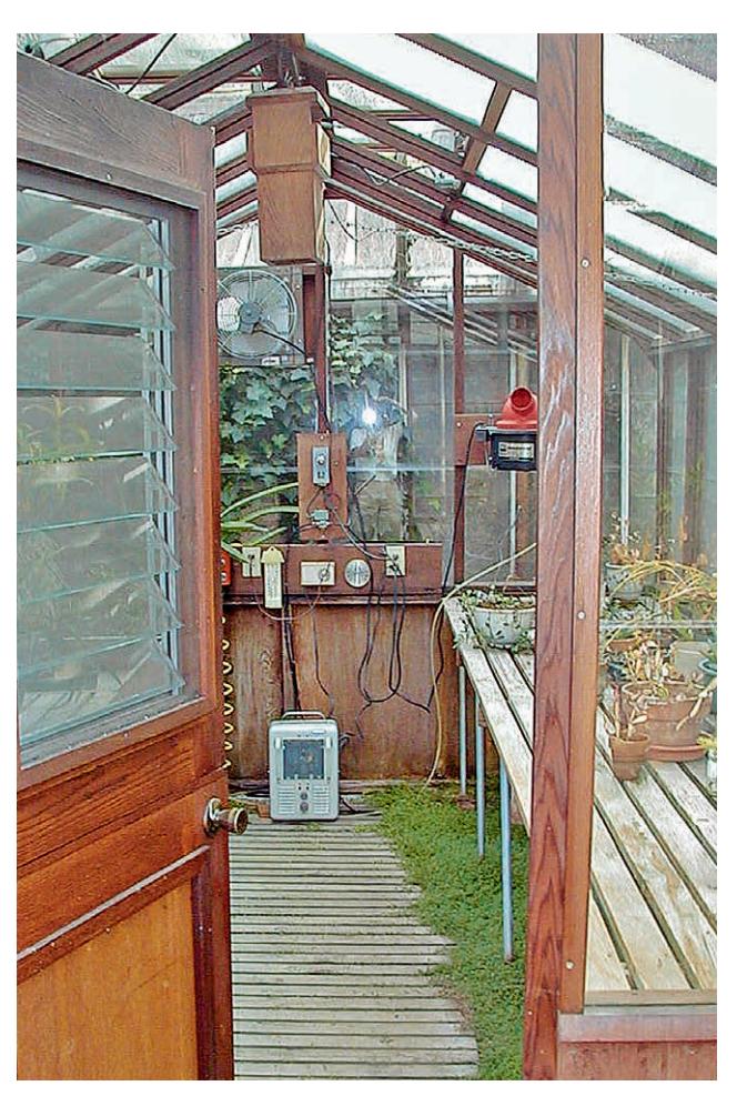 A small portable electric space heater on the floor of a greenhouse.