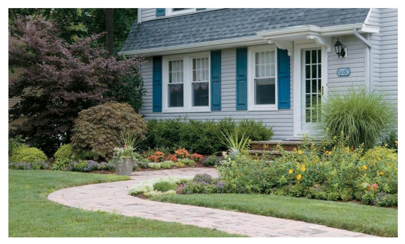 Front yard landscaping with varied beds of flowers and shrubs.