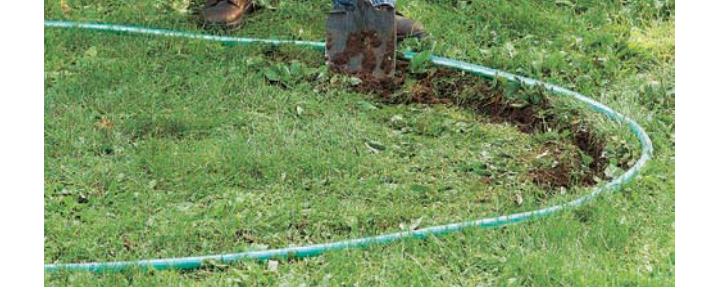 A garden hose laid out on the ground to outline a new garden bed